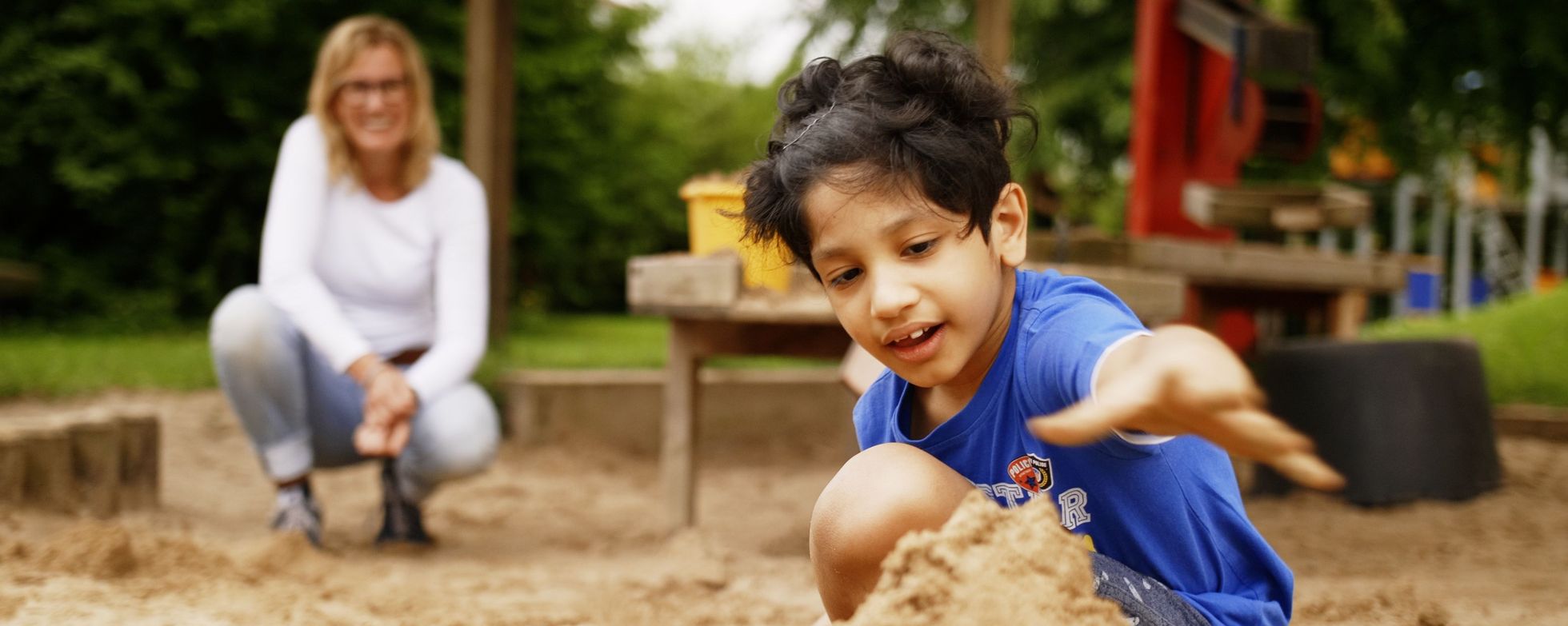 Spielender Junge im Vordergrund, Erzieherin weiter hinten. Spielender Junge im Vordergrund, Erzieherin weiter hinten.