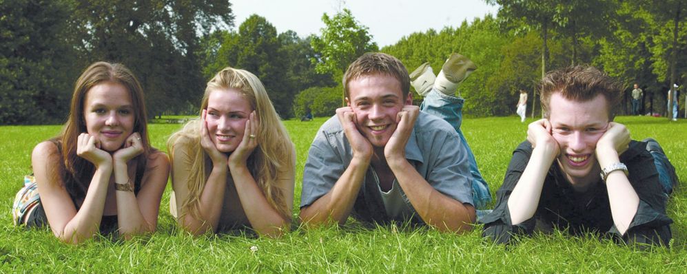 4 junge Menschen liegen bäuchlings im Grass 4 junge Menschen liegen bäuchlings im Grass